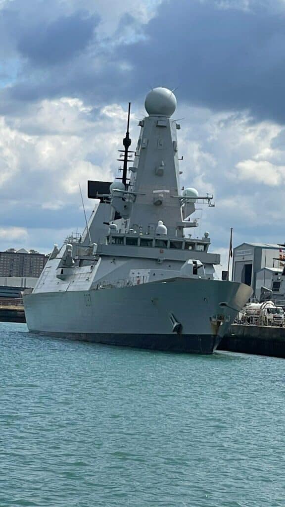 A large gray warship docked in the harbor